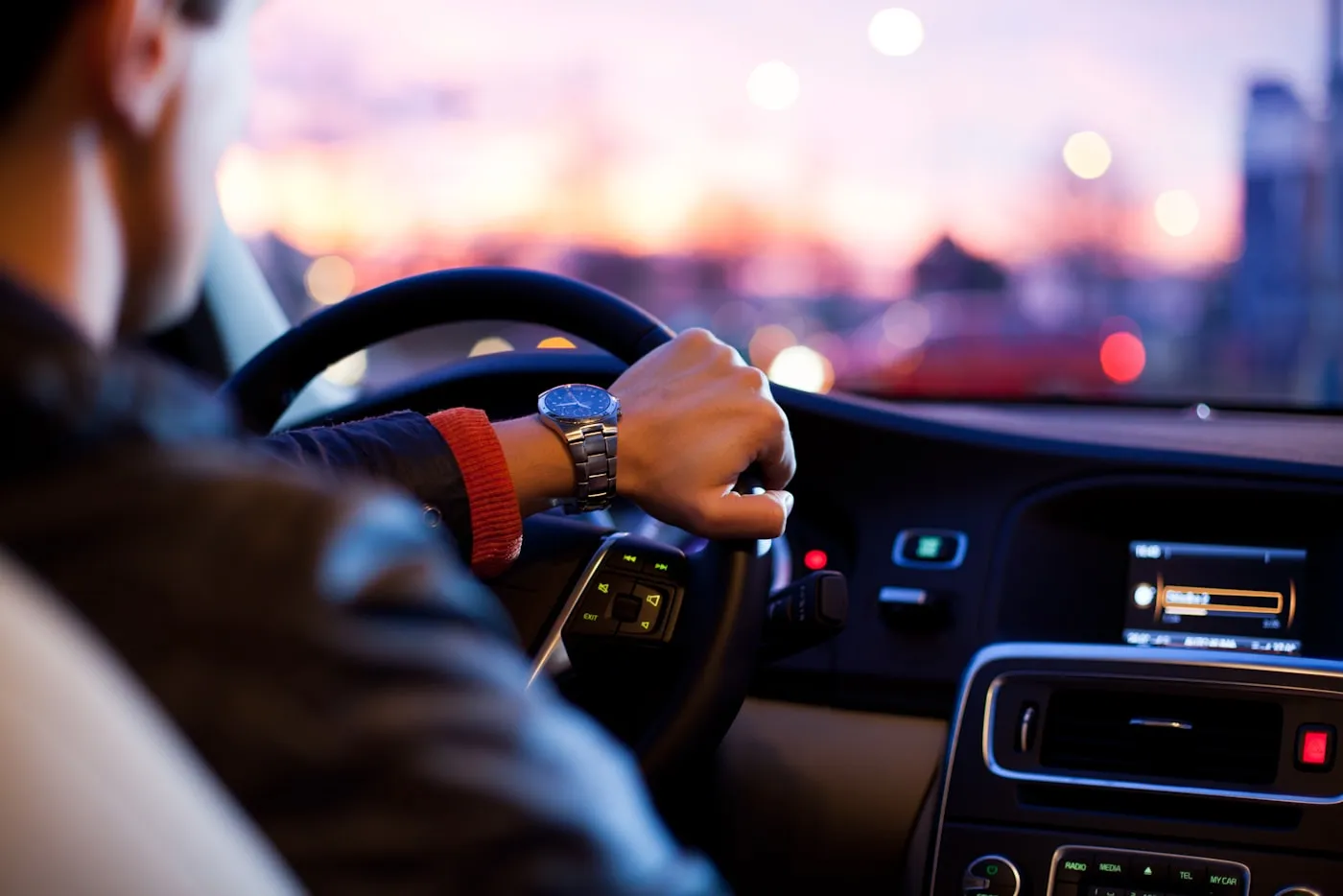 Hand am Lenkrad eines Autos in der Abenddämmerung